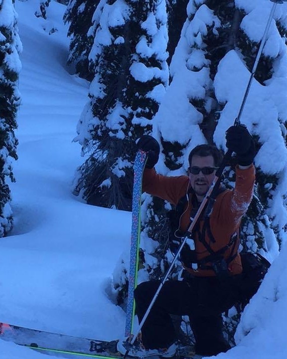 Backcountry skier moving through deep snow among heavily snow-covered trees