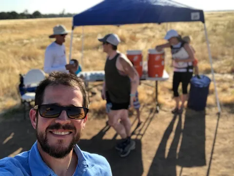 Randall Stone volunteering at a shaded community endurance-event aid station in dry open country